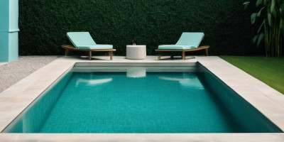 Photo montrant une piscine rectangulaire et moderne, entourée de margelles claires et d’un cadre épuré. Deux chaises longues turquoise sont disposées de part et d'autre d'une petite table ronde blanche, créant un espace de détente minimaliste. En arrière-
